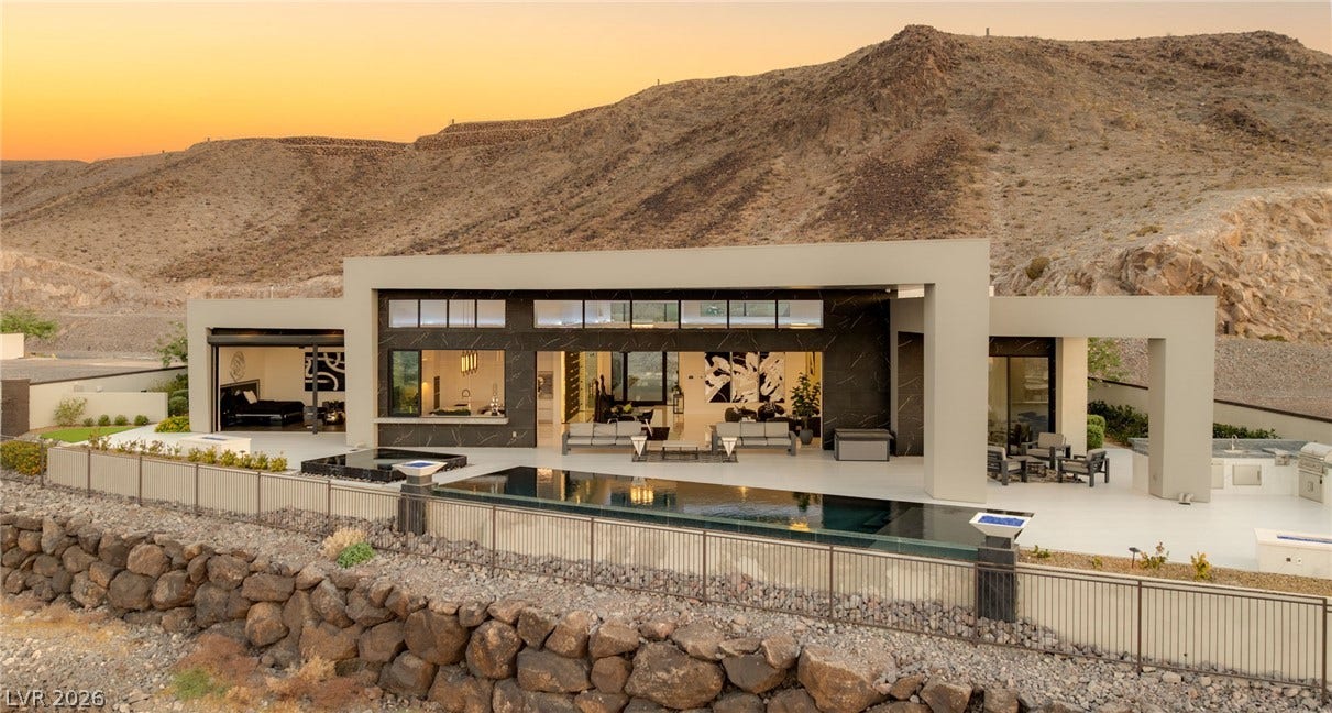 4 Chisel Crest Court, Henderson, NV 89012 A modern architectural facade rises against a dramatic mountain backdrop alongside a sleek infinity pool.