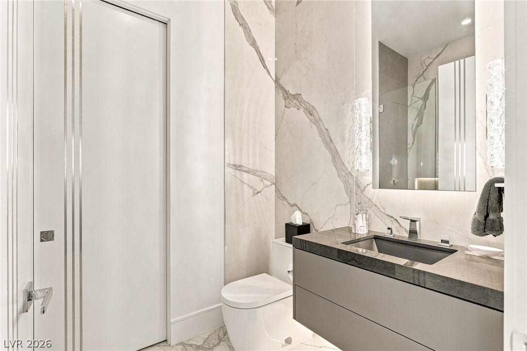 4 Chisel Crest Court, Henderson, NV 89012 Floor-to-ceiling stone tile accents and a floating vanity define this modern powder room.