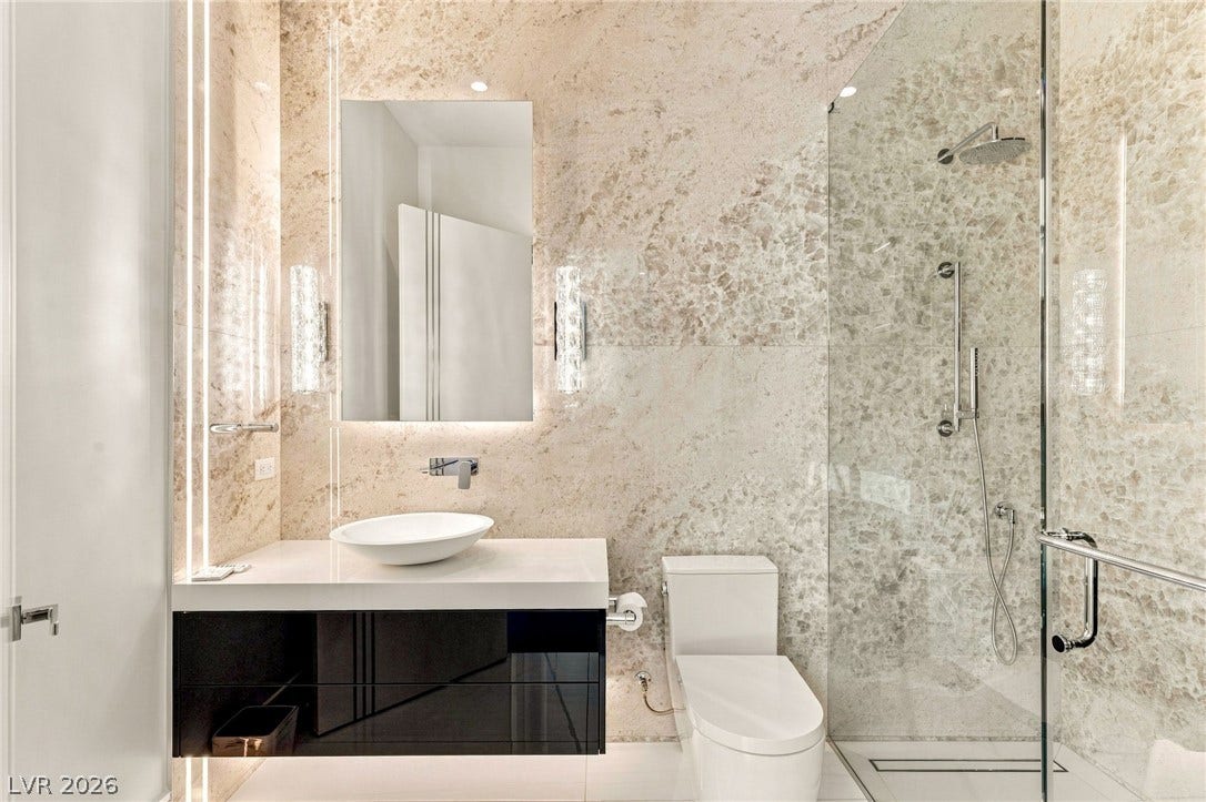 4 Chisel Crest Court, Henderson, NV 89012 Floor-to-ceiling stone tile surrounds a floating vanity and frameless glass shower.