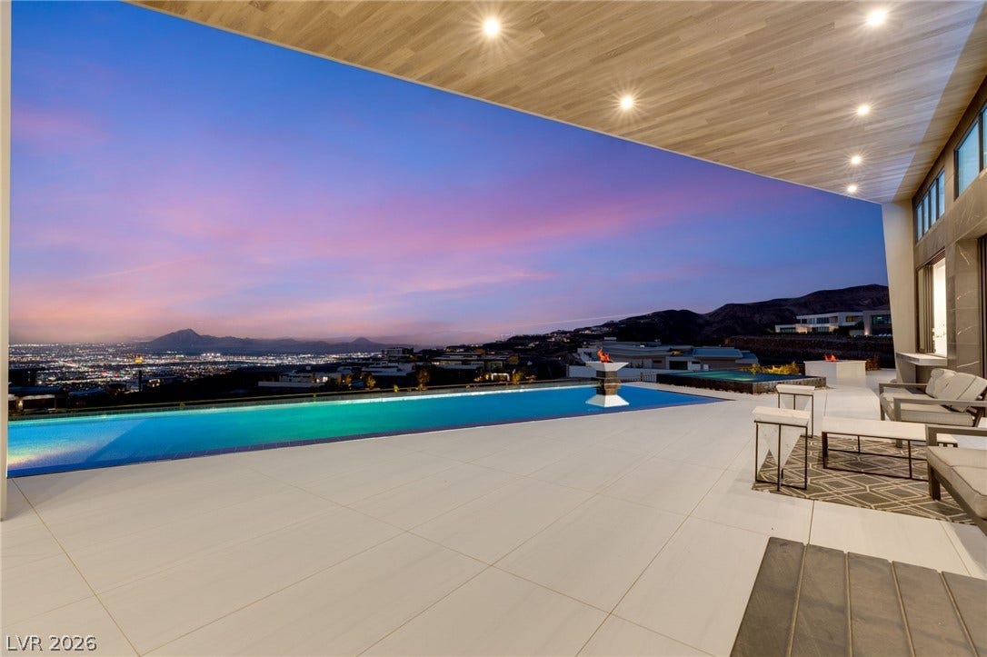 4 Chisel Crest Court, Henderson, NV 89012 An expansive covered terrace framing panoramic city light and mountain vistas beyond a sleek infinity pool.