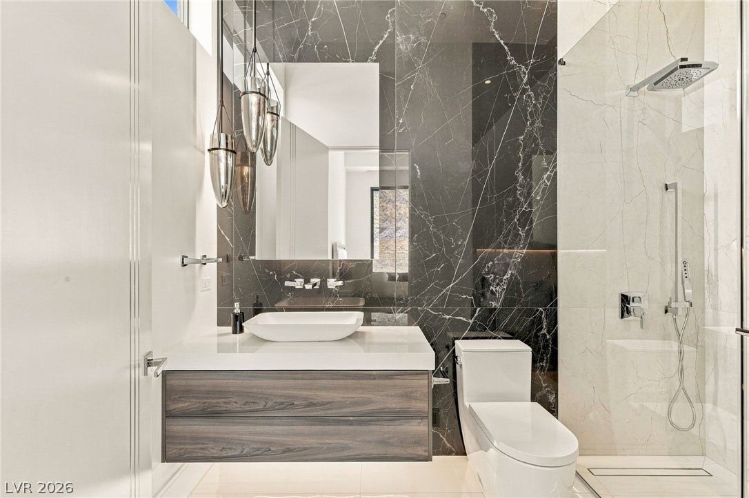 4 Chisel Crest Court, Henderson, NV 89012 Dramatic dark marble tile walls create a striking contrast in this contemporary bathroom space.