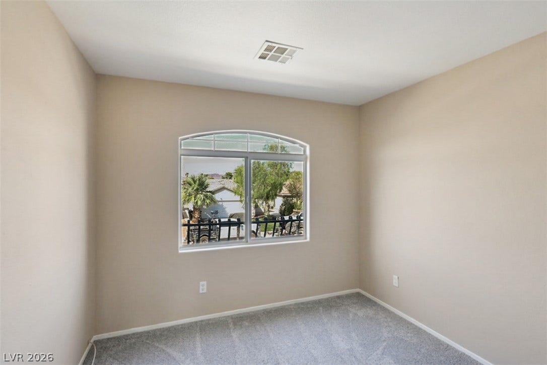 A quiet bedroom offers an arched window framing verdant outdoor views.