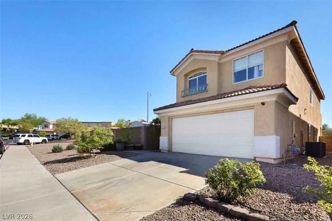 A classic stucco residence presents a concrete driveway and an attached two-car garage.