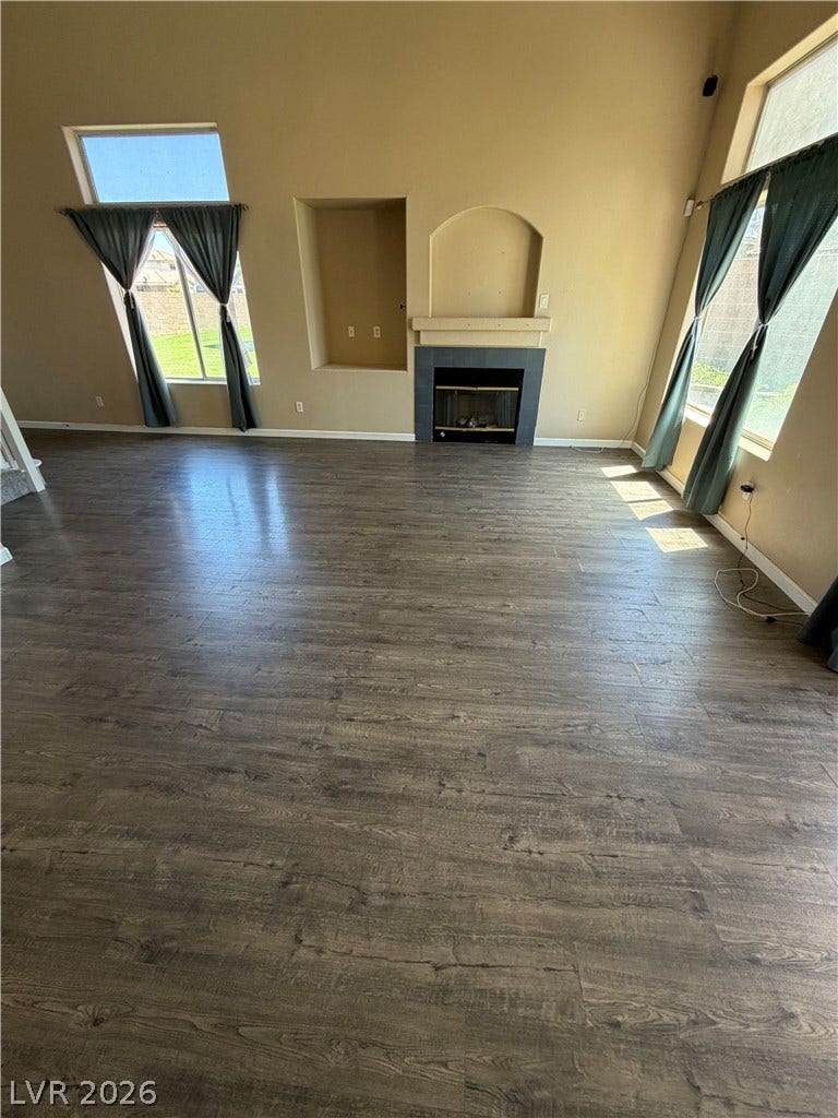 A welcoming living space features warm flooring, a cozy fireplace, and unique windows.