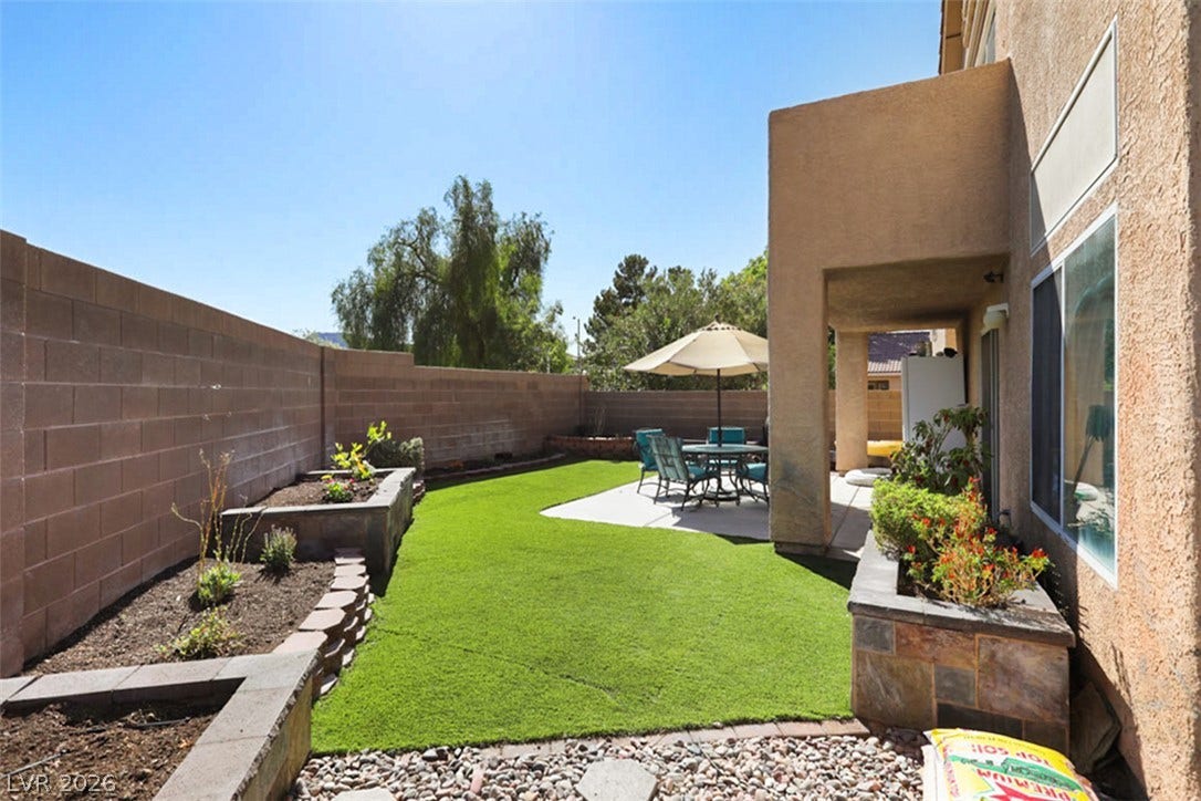 A private yard with artificial turf and a covered patio offers outdoor leisure.