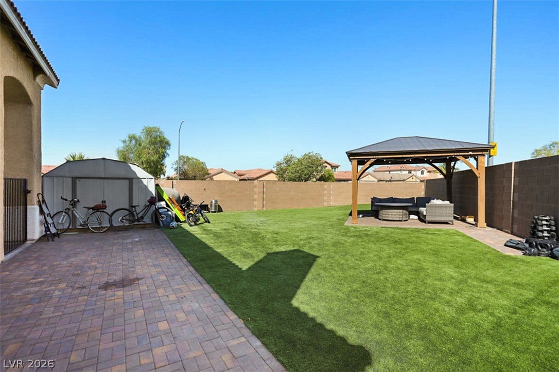 A spacious backyard with an inviting gazebo and low-maintenance artificial turf.