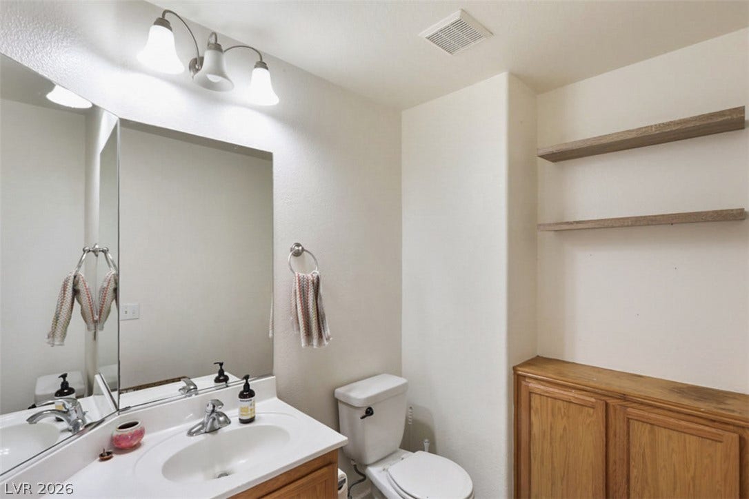 A bright bathroom with a vanity sink and a toilet offers functional comfort.