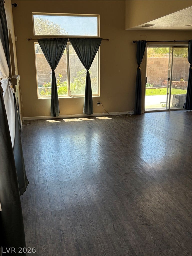 Rich wood flooring complements bright windows and a glass slider opening to the backyard.