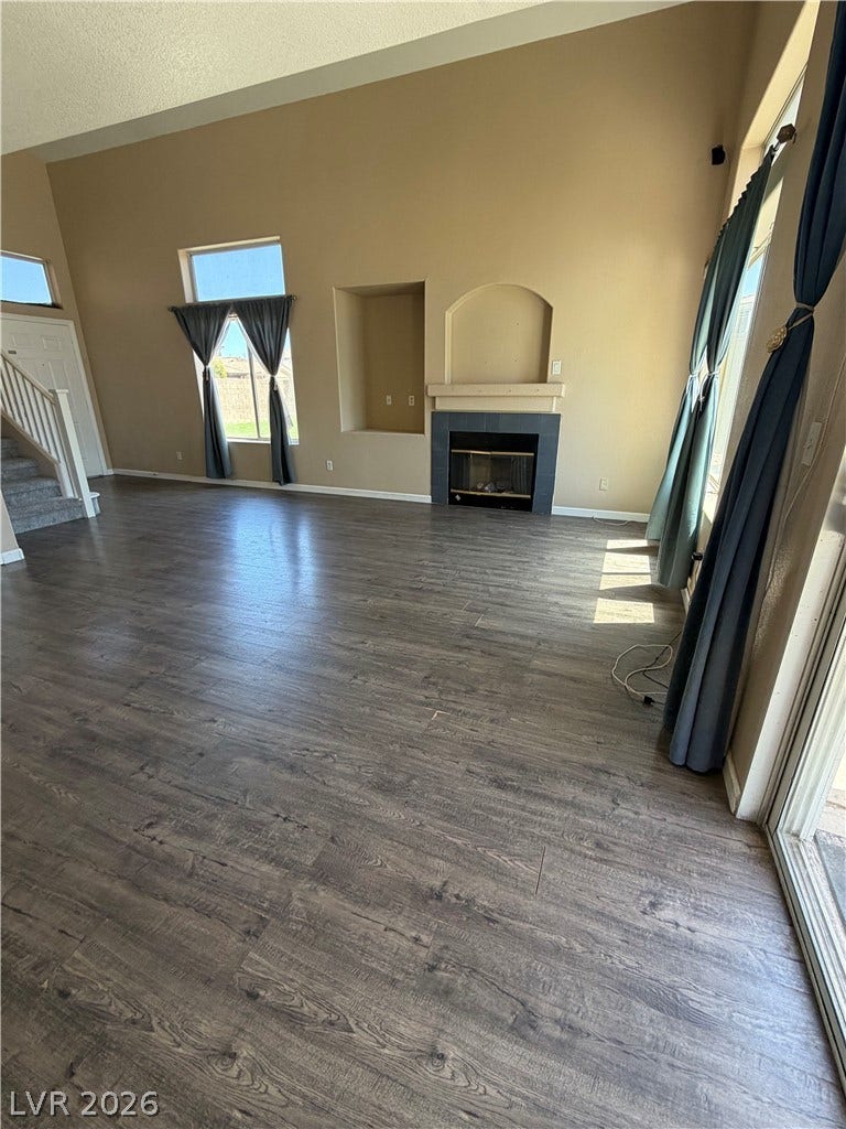 A spacious living area features high ceilings, rich hardwood flooring, and a welcoming fireplace, perfect for relaxation.