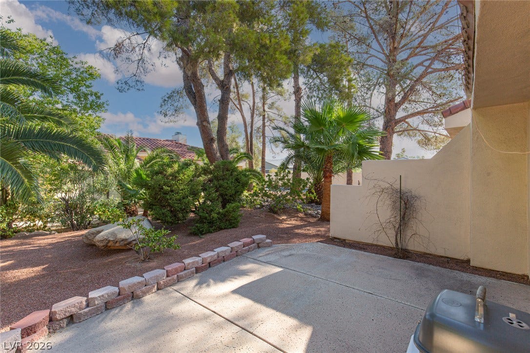 2882 Bridgepointe Drive, Las Vegas, NV 89121 Mature trees and desert plantings surround a quiet concrete patio space.