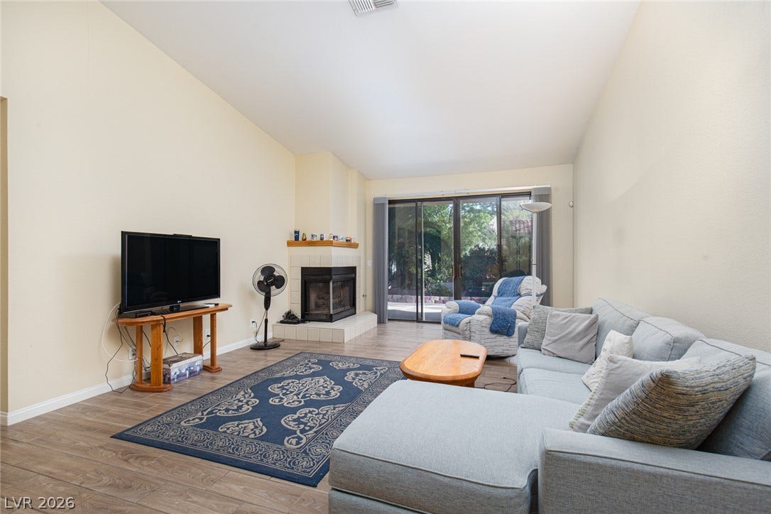 2882 Bridgepointe Drive, Las Vegas, NV 89121 A spacious living room features vaulted ceilings, tile flooring, and a cozy corner fireplace.