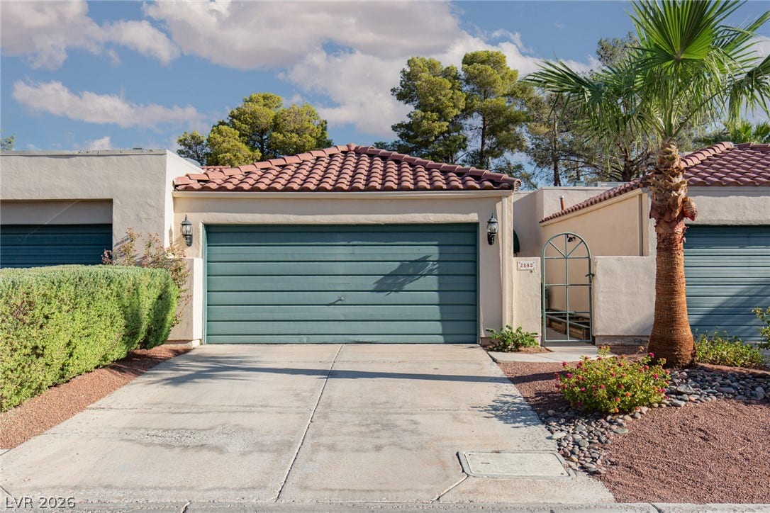 2882 Bridgepointe Drive, Las Vegas, NV 89121 A concrete driveway leads to the attached garage under a classic tile roof.