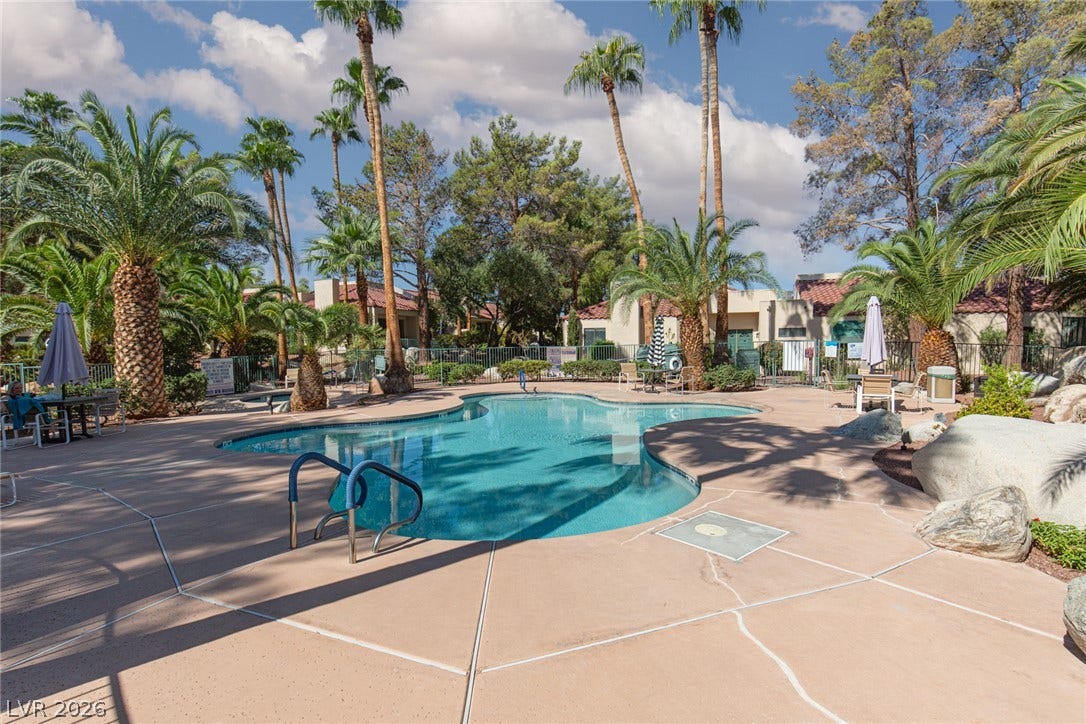 2882 Bridgepointe Drive, Las Vegas, NV 89121 Lush palm trees surround a sparkling community swimming pool with concrete decking.