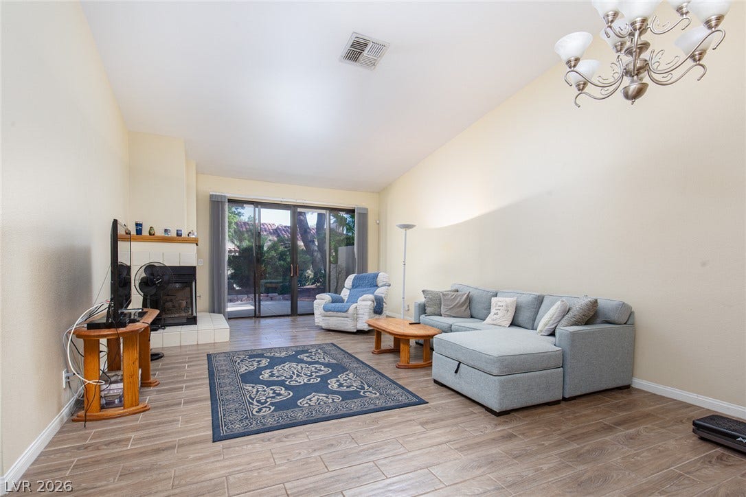 2882 Bridgepointe Drive, Las Vegas, NV 89121 Sliding glass doors open to the outdoors, framing a fireplace and wood-look tile floors.