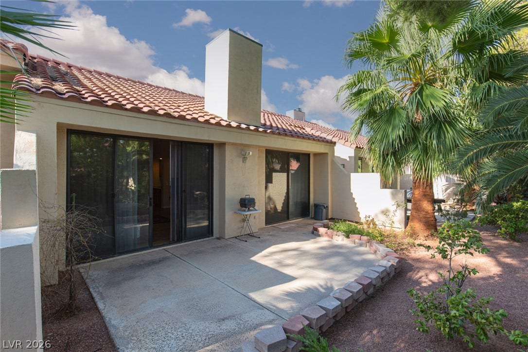 2882 Bridgepointe Drive, Las Vegas, NV 89121 Sliding glass doors open directly onto a private concrete patio surrounded by desert landscaping.