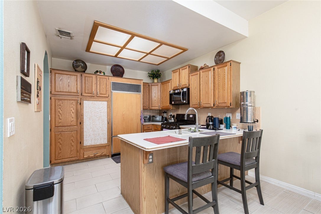 2882 Bridgepointe Drive, Las Vegas, NV 89121 Ample wooden cabinetry and a central prep island anchor this functional kitchen layout.