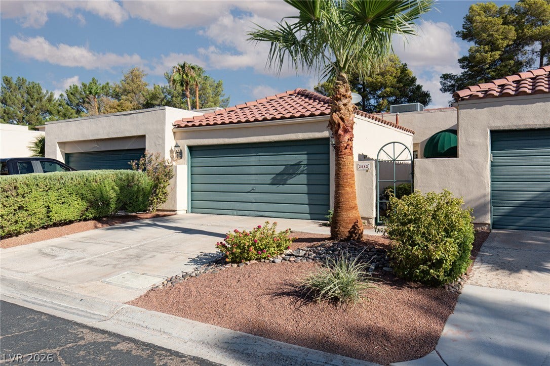 2882 Bridgepointe Drive, Las Vegas, NV 89121 Spanish tile roofing and low-maintenance desert landscaping frame the concrete driveway and private garage.