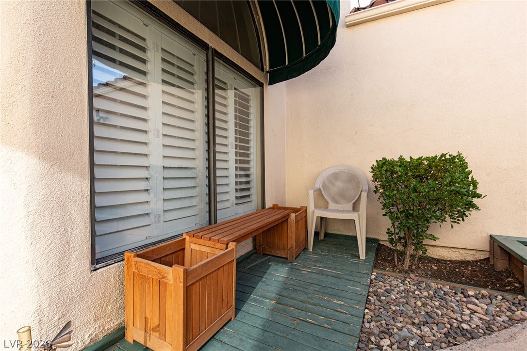 2882 Bridgepointe Drive, Las Vegas, NV 89121 A secluded outdoor patio features a wooden walkway and an overhead awning.