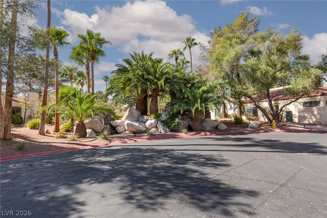 2882 Bridgepointe Drive, Las Vegas, NV 89121 Lush tropical palms and native trees frame the manicured stone landscaping beside the paved street.