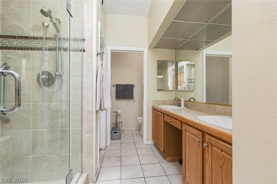2882 Bridgepointe Drive, Las Vegas, NV 89121 Tiled flooring and a glass-enclosed walk-in shower anchor this functional bathroom layout.