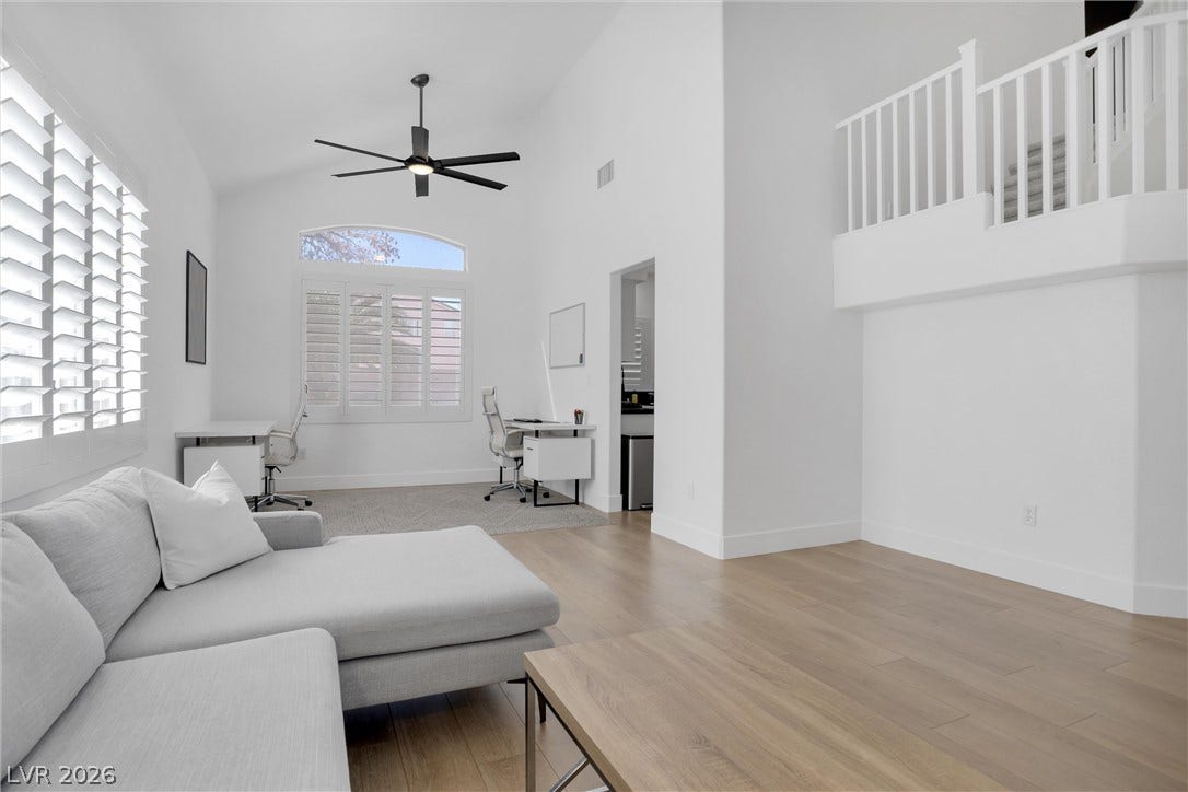 337 Teal Ridge Hills Drive, Henderson, NV 89014 Double-height ceilings and tall windows elevate this open living area finished with light wood floors.