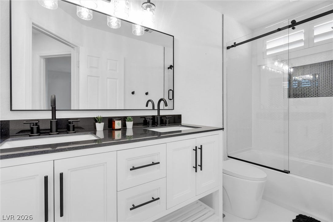 337 Teal Ridge Hills Drive, Henderson, NV 89014 Crisp white cabinetry contrasts beautifully with dark stone countertops in this modern bathroom design.