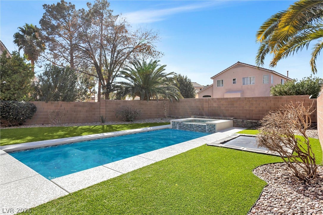 337 Teal Ridge Hills Drive, Henderson, NV 89014 An inviting backyard features a sparkling swimming pool, integrated spa, and manicured green lawns.