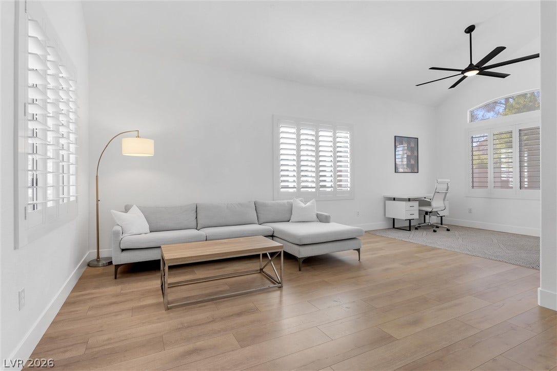 337 Teal Ridge Hills Drive, Henderson, NV 89014 Smooth wood floors pair with tall windows and classic plantation shutters in this open living space.