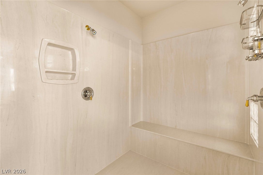 Seamless wall panels and a built-in bench elevate this spacious shower design.