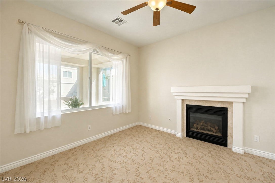 A classic fireplace with a detailed mantel anchors this comfortable room featuring soft carpeted flooring.
