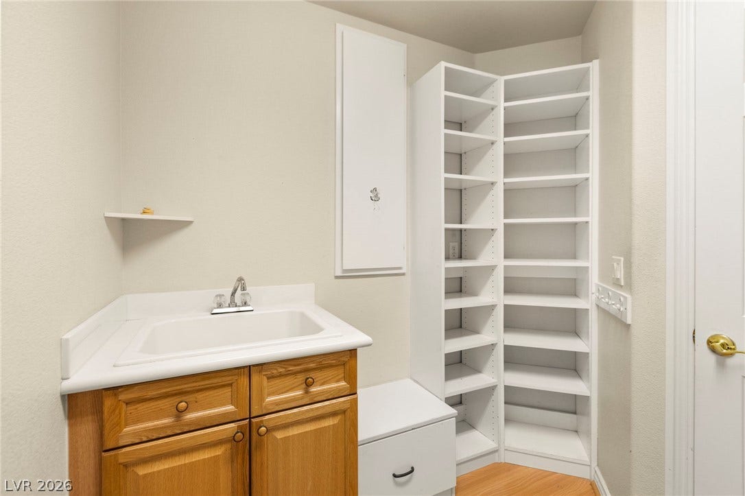 Custom built-in shelving pairs with a functional utility sink and warm wood flooring.