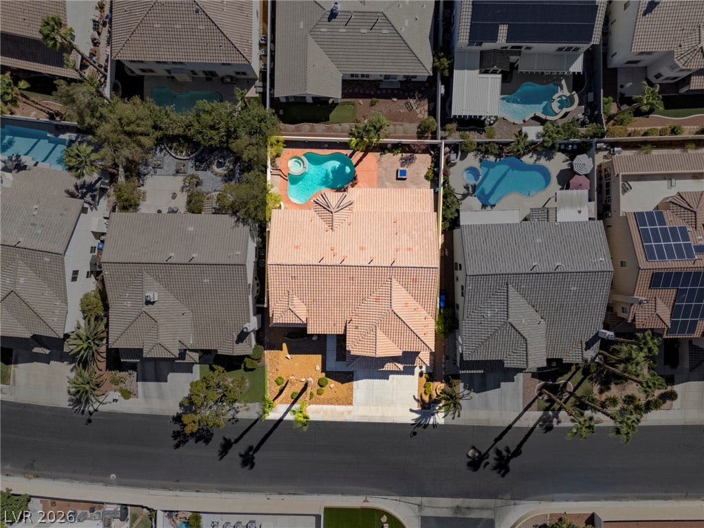 An aerial perspective reveals a barrel tile roof alongside a backyard pool and spa.
