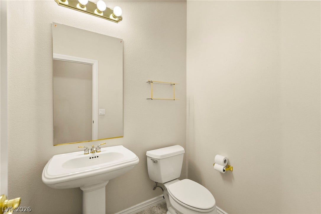 A classic pedestal sink paired with golden accents coordinates beautifully in this powder room.