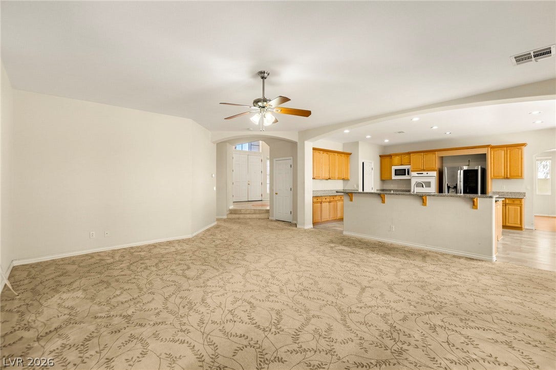 An open floorplan seamlessly connects the carpeted living area to the adjacent kitchen.