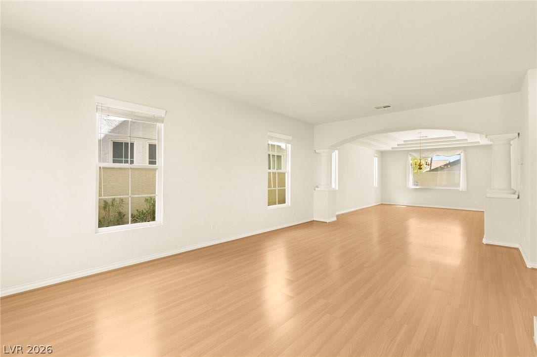 Leading into formal dining room with gleaming wood floors and a structural archway define this light-filled, open-concept secondary living room.