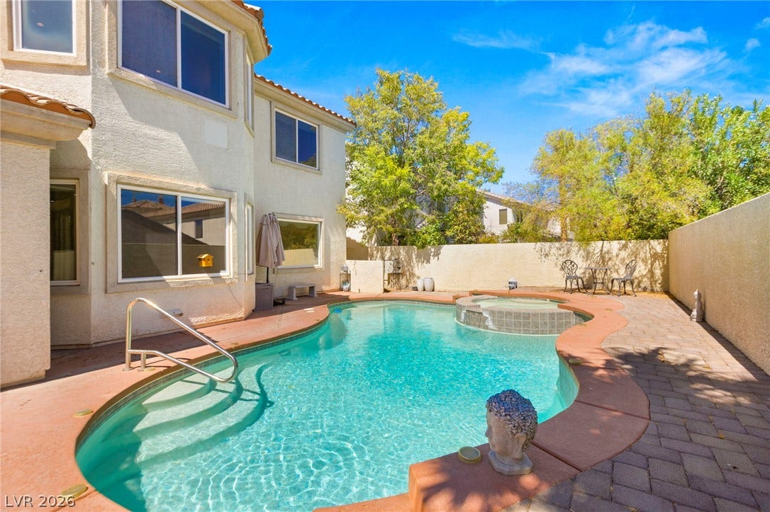 An inviting backyard oasis features a shimmering private swimming pool and integrated spa.