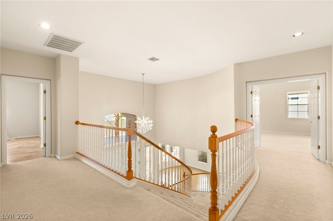 An open upper hallway features a curved banister overlooking the lower level.