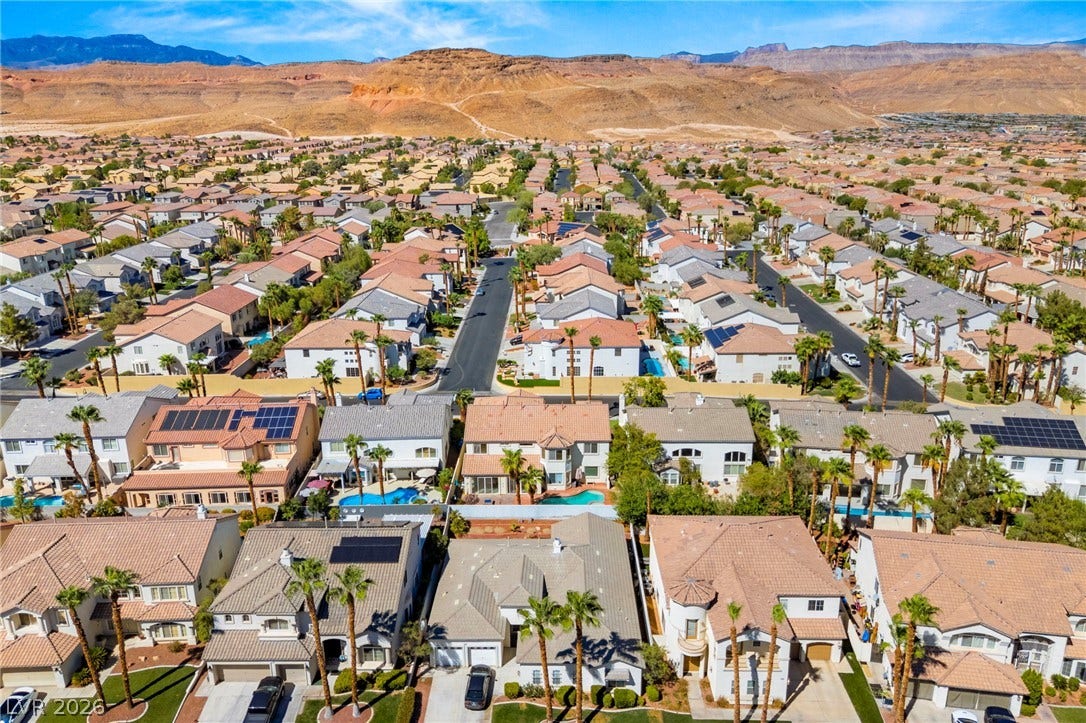 An expansive neighborhood panorama showcases neat residential streets framed by dramatic desert mountains.