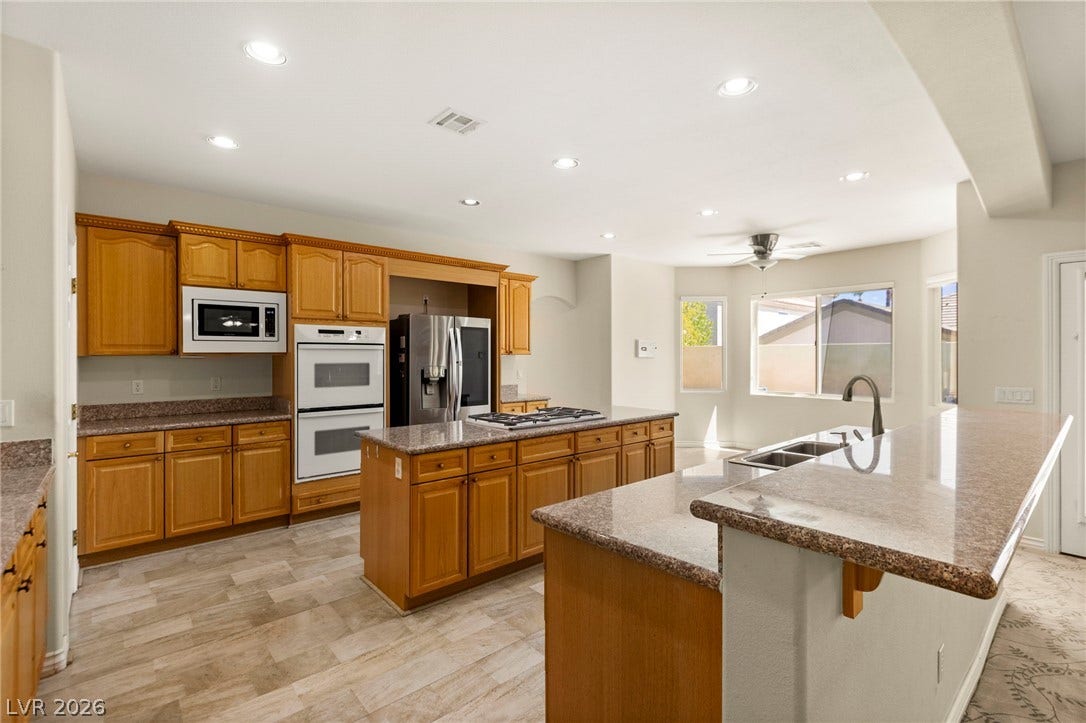 Rich wood cabinetry, double island and expansive granite countertops define this open, functional gourmet kitchen.