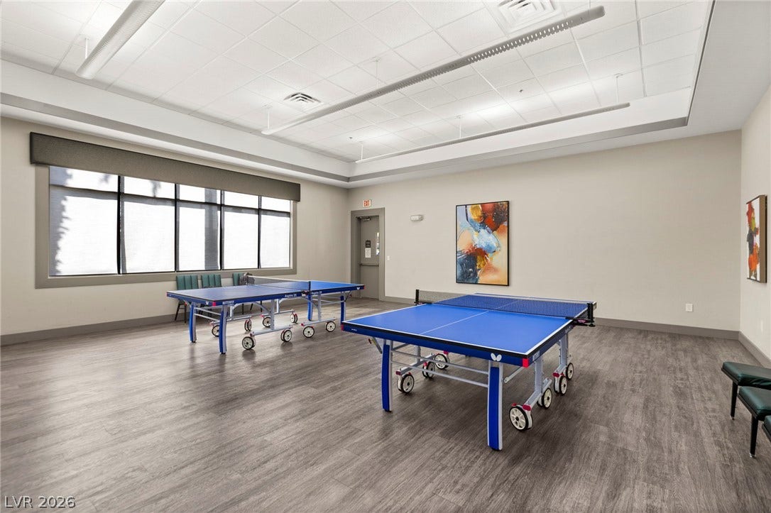 A spacious recreational ping-pong room features durable wood-look flooring and a recessed ceiling design.