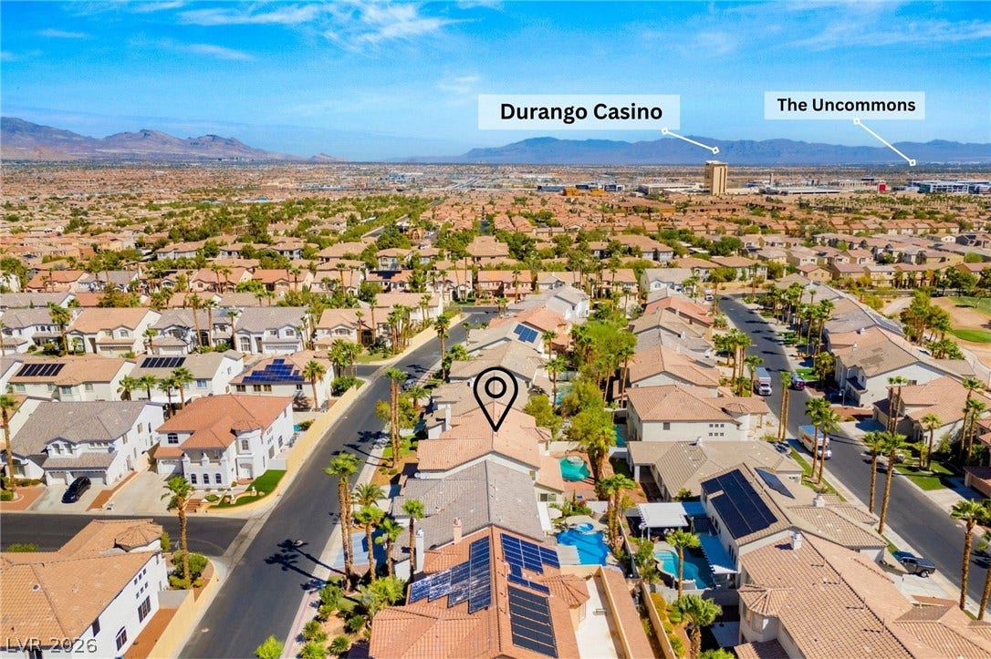 An aerial perspective showcases the surrounding neighborhood under clear blue desert skies.