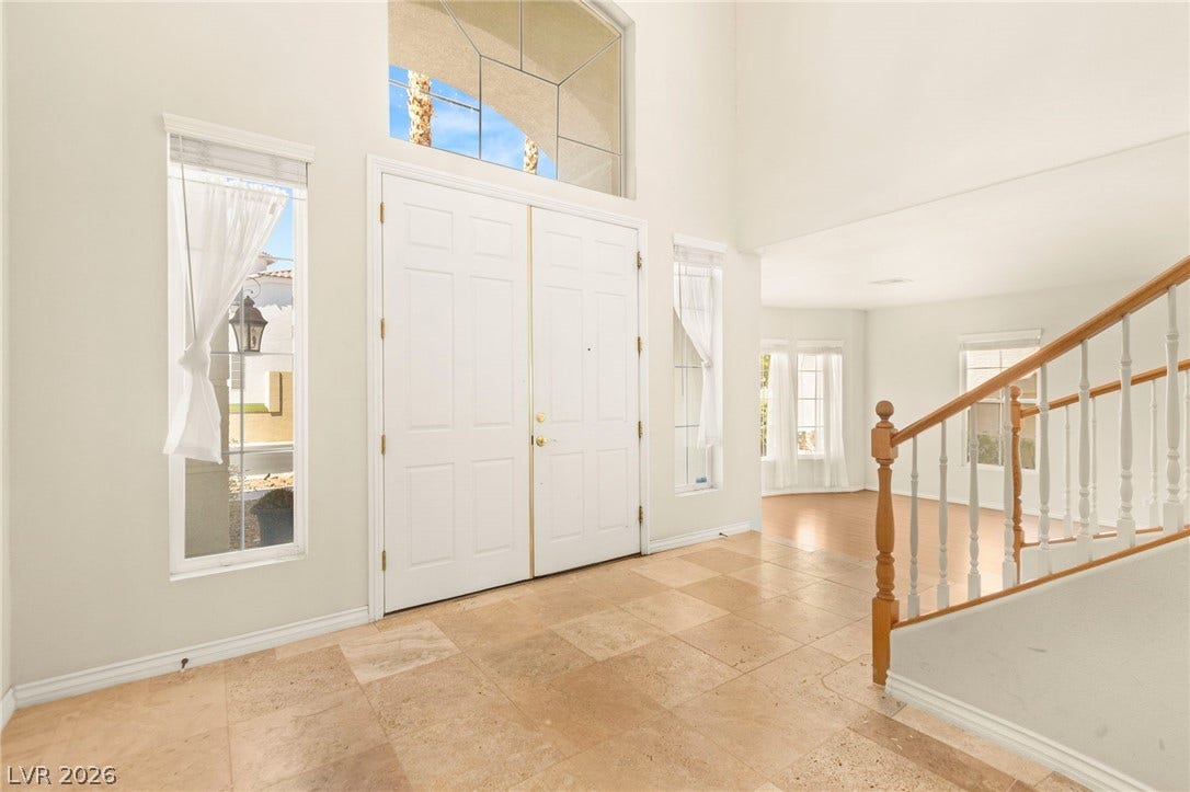 Double front doors open into a soaring foyer featuring travertine  flooring and soaring high ceilings.