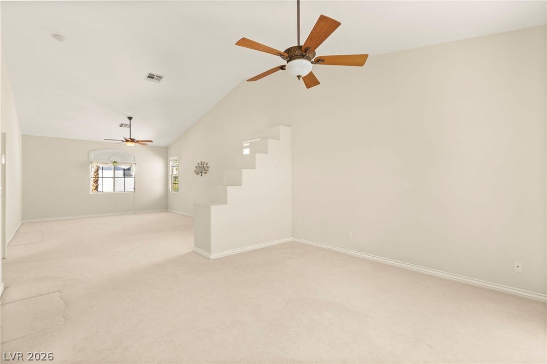 Vaulted ceilings and soft carpeting define this versatile sitting area, in the ultra-spacious primary bedroom.