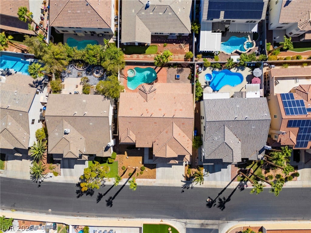 An aerial view showcases tile roofing and a backyard pool in a suburban neighborhood.