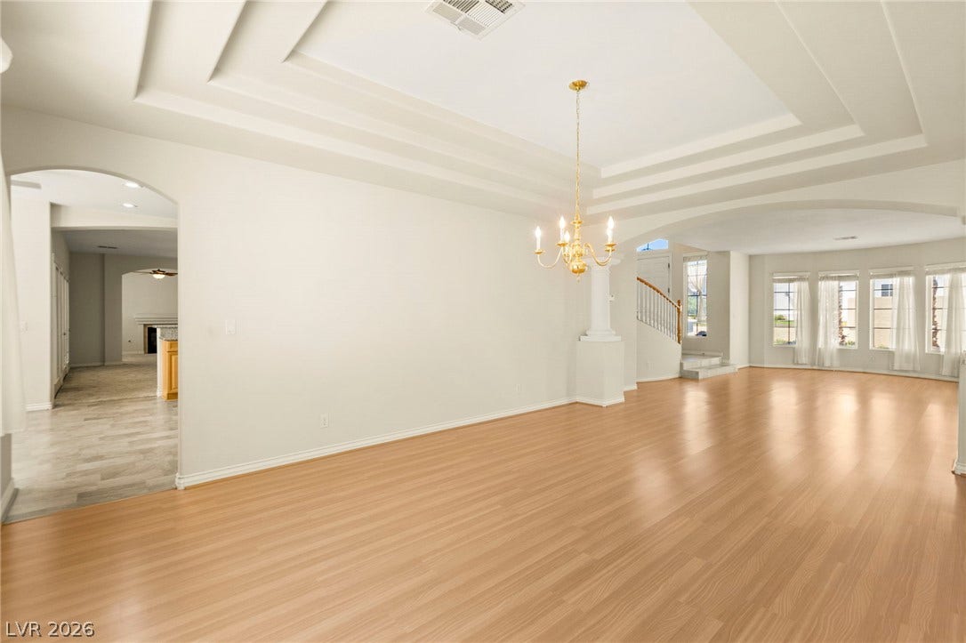 Spacious formal dining room with Gleaming hardwood floors and a tiered ceiling create an elegant atmosphere with natural lighting.