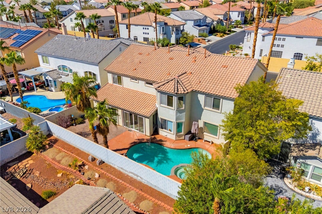 An aerial perspective showcases the back of this private oasis featuring a pool and  mature landscaping in the massive backyard.