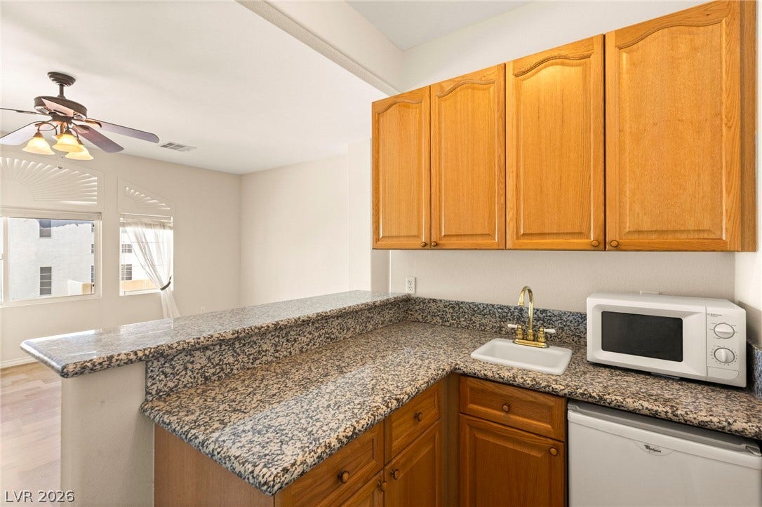 Granite counters and wood cabinetry define this functional bar area overlooking the enclosed den that serves as a second primary (6th bedroom option)