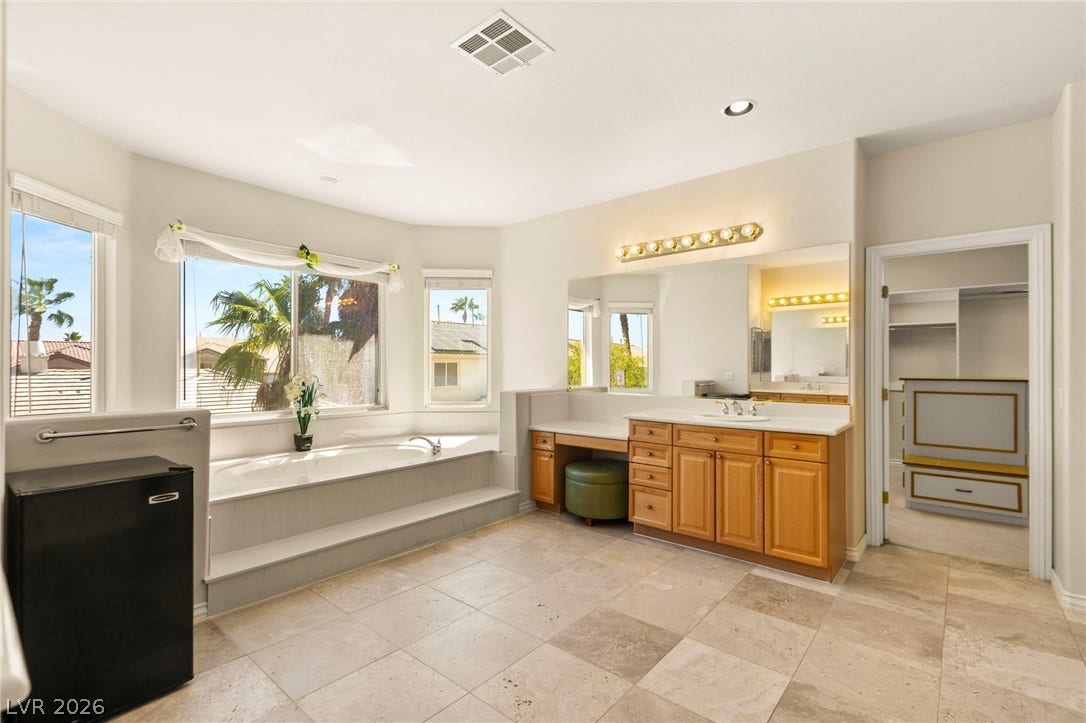 A spacious bathroom features a raised soaking tub and premium tiled flooring.