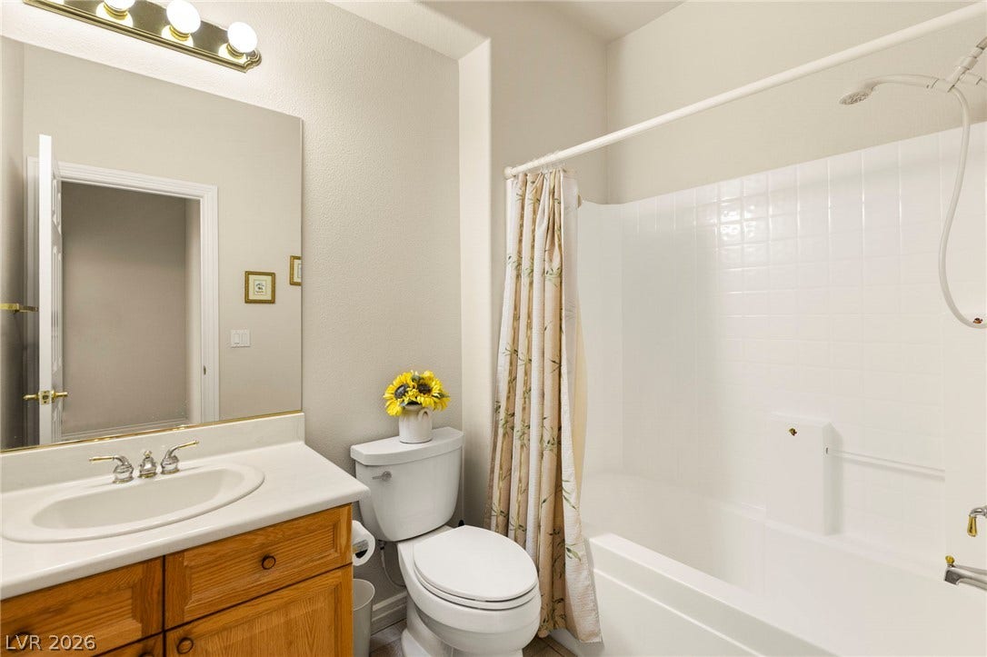 Main floor bathroom with classic bathtub and tile surround complement the wooden vanity.
