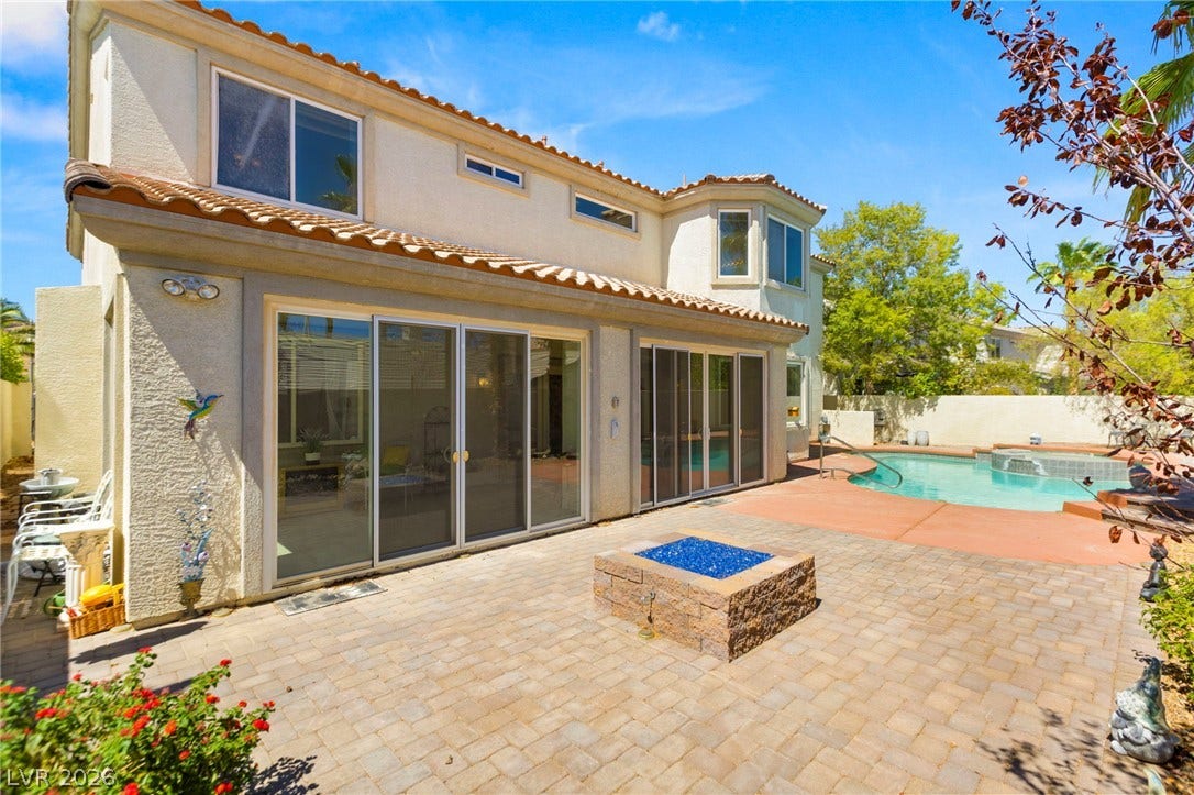 Inviting paved patio area features a built-in fire pit adjacent to the pool.